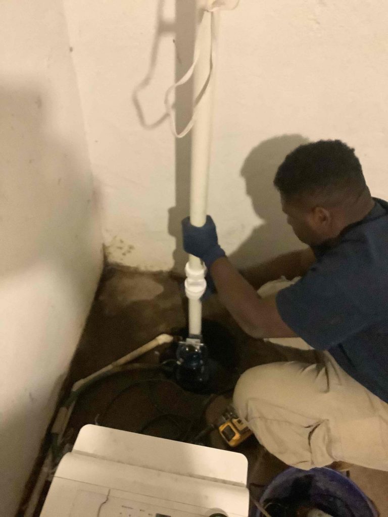 PlumbPRO technician installs a sump pump in a basement